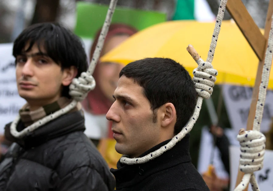 Jovens protestam contra pena de morte para homossexuais, em Berlim. Na imagem, dois homens estão com cordas amarrados em seus pescoços, simulando um enforcamento