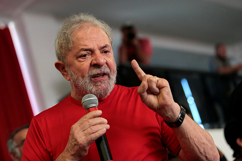 Ex-presidente Lula aparece falando de camisa vermelha, com um microfone na mão